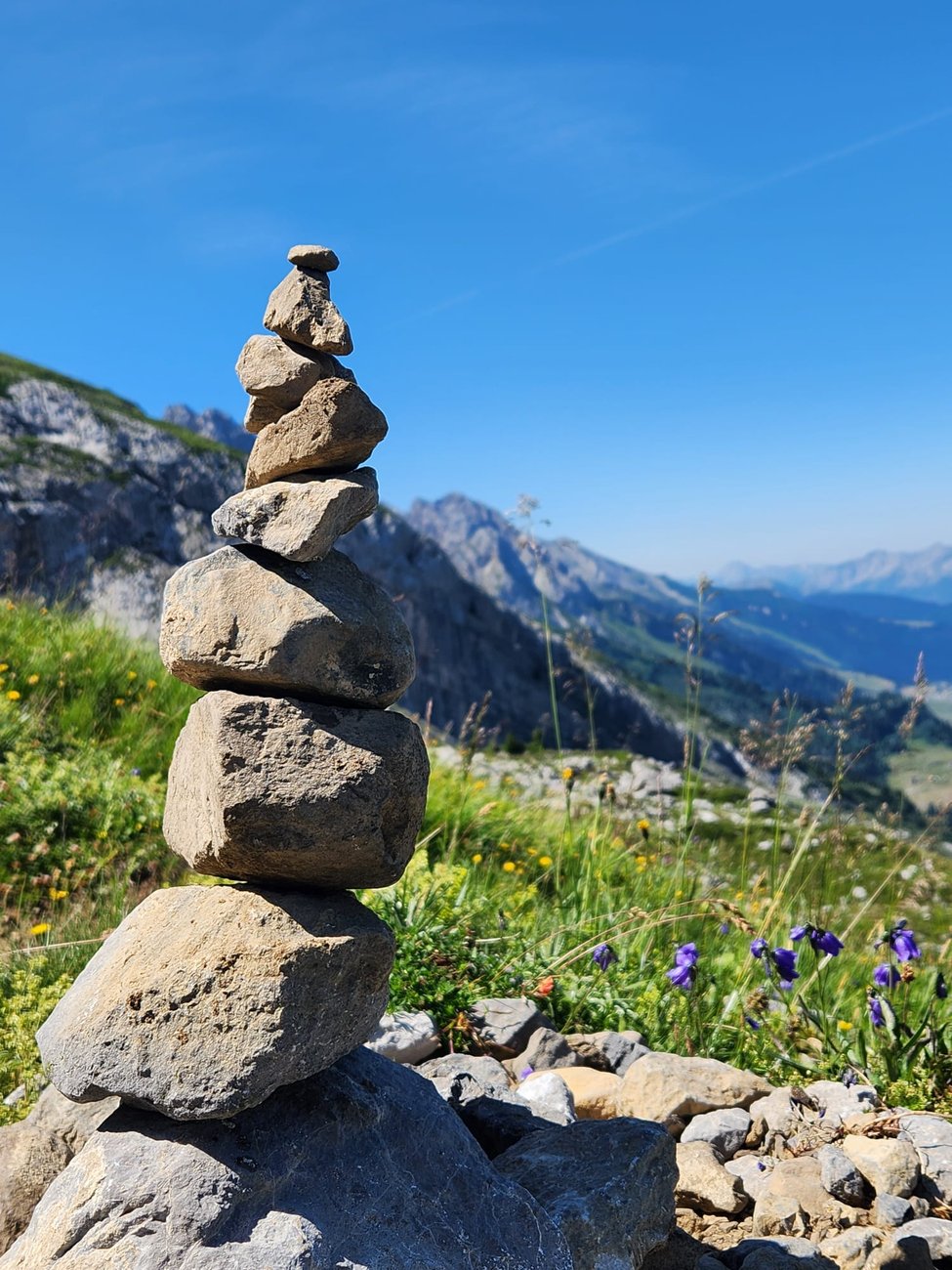 Cairn de pierres en équilibre sur un sentier de montagne, symbole des deux piliers de l'école